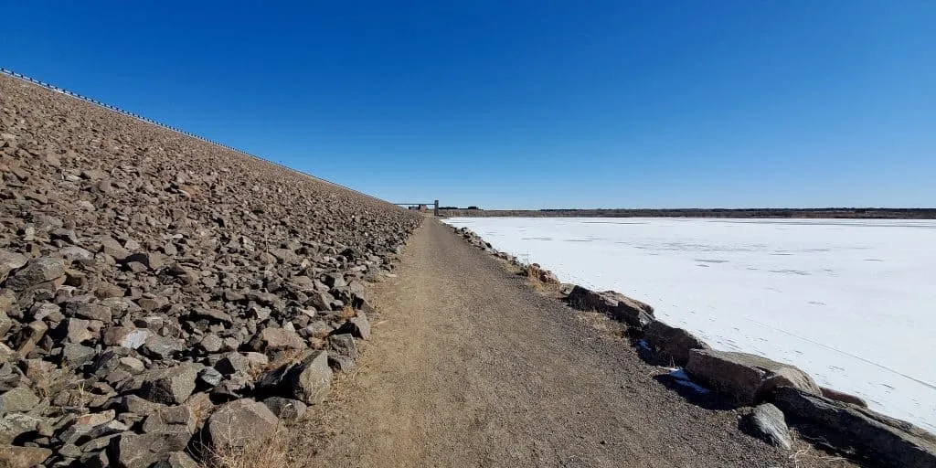Dam Trail in Cherry Creek State Park. Dam on the left of trail, frozen reservoir on the rigth