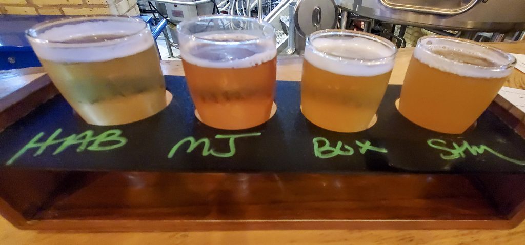 Beer tasting flight; four tasting glasses set into a wooden board.