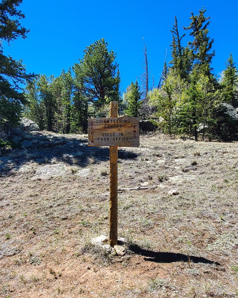 Wooden sign at the start of the orienteering course at Eleven Mile State Park.  Evergreens in the background