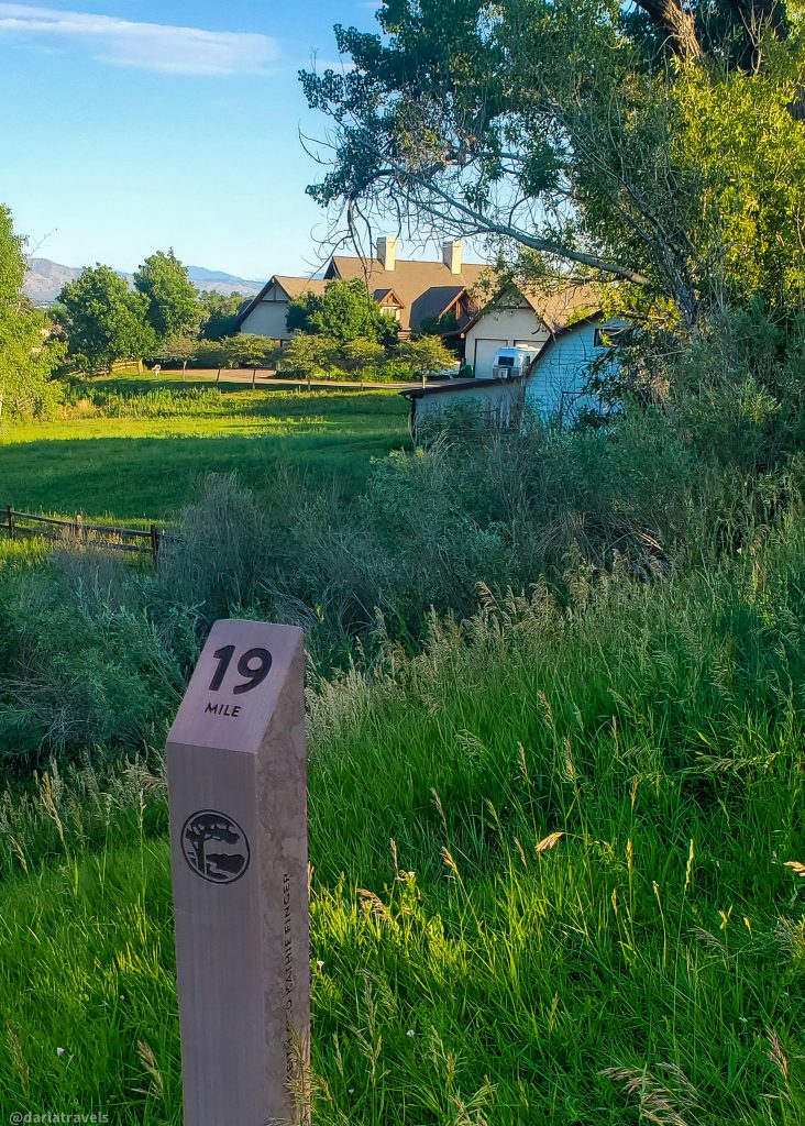 trail mile marker reading "19" in the foreground, grassy area with large homes in the midground