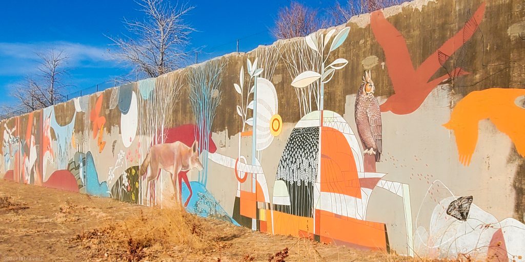 concrete wall covered with a mural of animal and plants