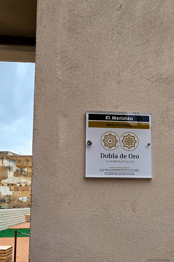 A close-up of a white sign with black text. The sign includes the name "El Maristan," "Ruta Turistica," and information about visiting hours in Spanish.