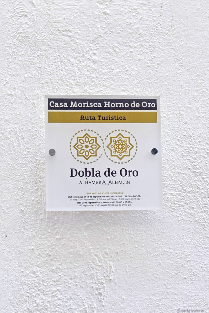 A close-up of a white sign with black text. The sign includes the name "Casa Morisca Horno de Oro," "Ruta Turistica," and information about visiting hours in Spanish.