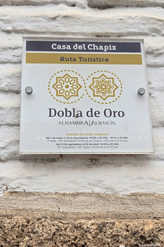 A close-up of a white sign with black text. The sign includes the name "Casa del Chapiz," "Ruta Turistica," and information about visiting hours in Spanish.
