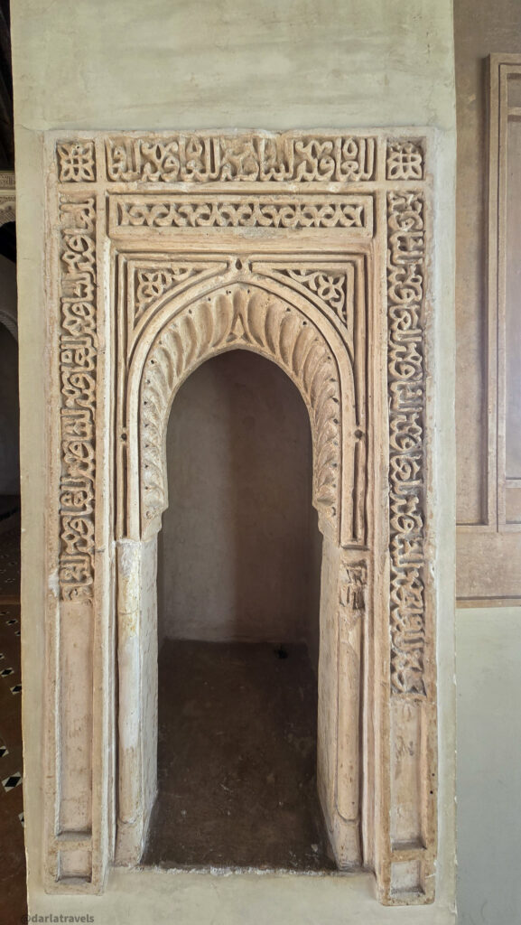 A close-up of an arched alcove with intricate carvings and decorative details. The alcove appears to be part of a larger wall structure.