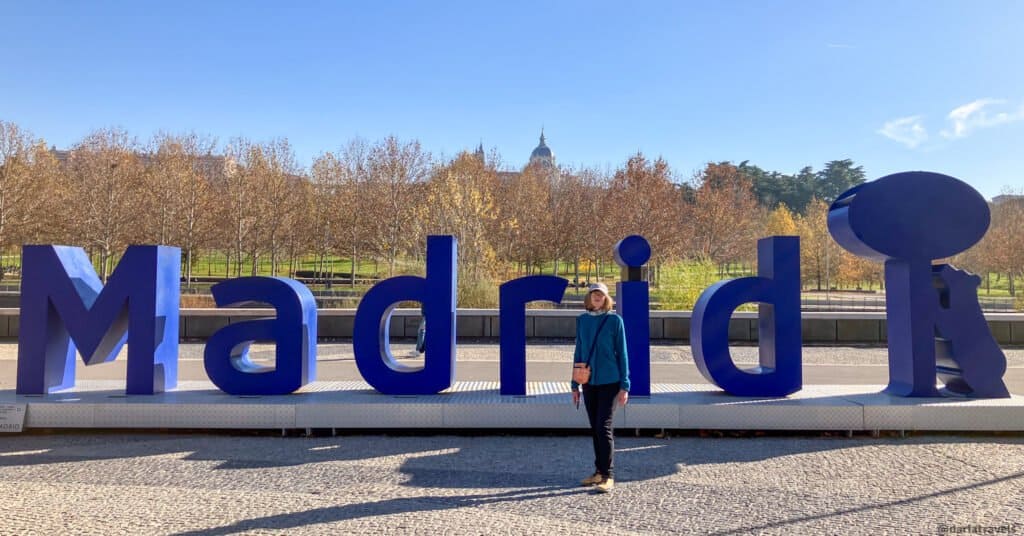 Blue "Letters sign" spelling "Madrid" with Madrid symbol of a bear and madrono tree; walks in Madrid's parks