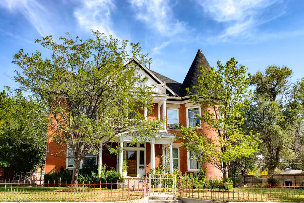 Red-brick Victorian home with turret and white-column porch in La Junta, Colorado