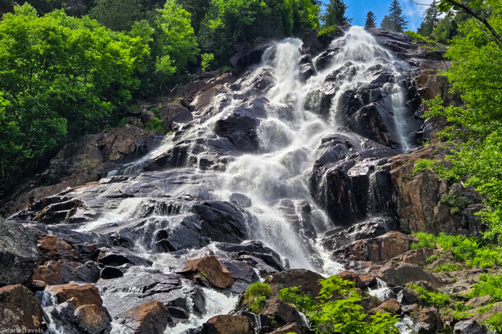 Waterfall at Chute Delaney flowing over rocks, surrounded by forest in Vallée Bras-du-Nord hiking area