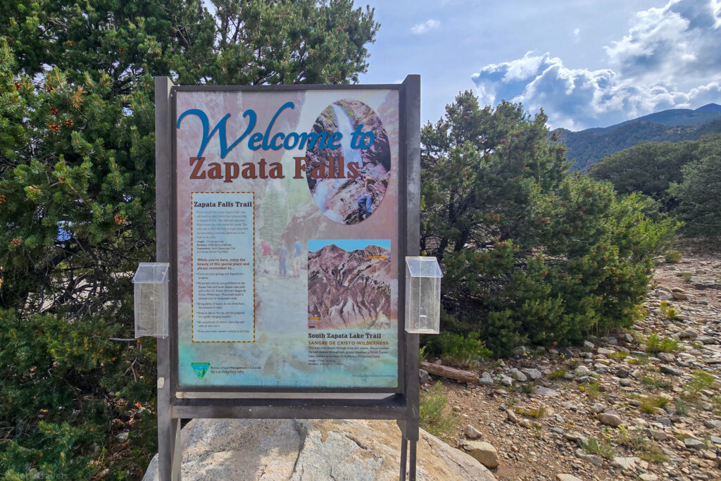 Informational sign at Zapata Falls trailhead with details on hiking routes and safety tips near Alamosa, Colorado