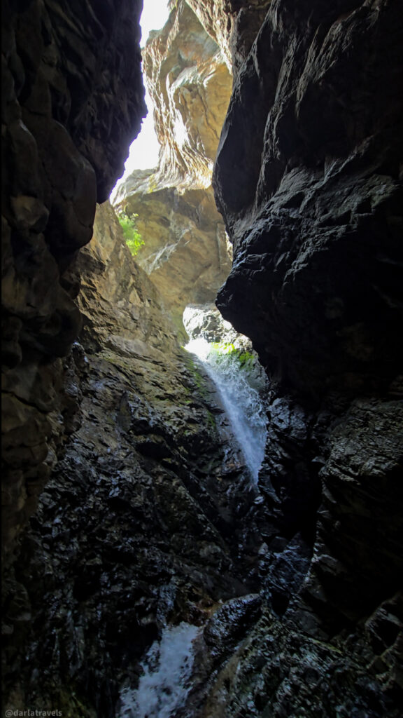 Zapata Falls cascading through narrow rocky gorge near Alamosa, Colorado, with sunlight on upper cliff face