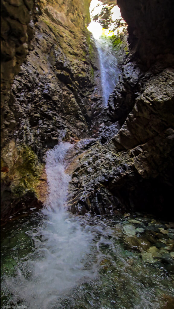 Zapata Falls cascading through narrow rocky gorge near Alamosa, Colorado, with sunlight on upper cliff face