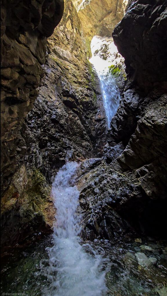 Zapata Falls cascading through narrow rocky gorge near Alamosa, Colorado, with sunlight on upper cliff face
