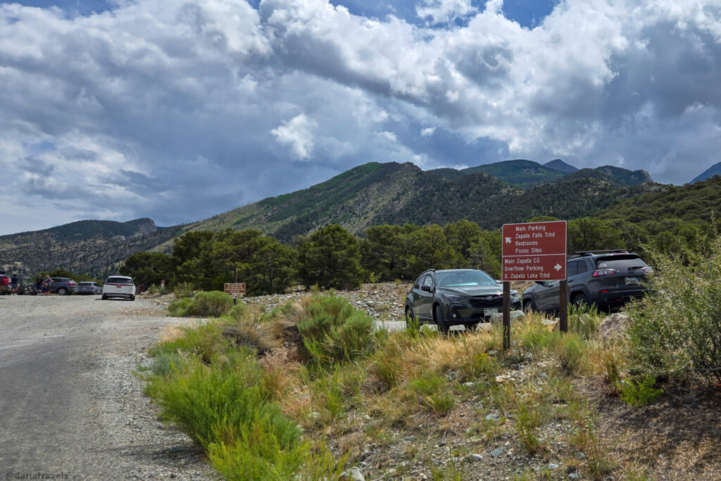 Parking area with trail and directional sign listing at Zapata Falls Trailhead and Campground