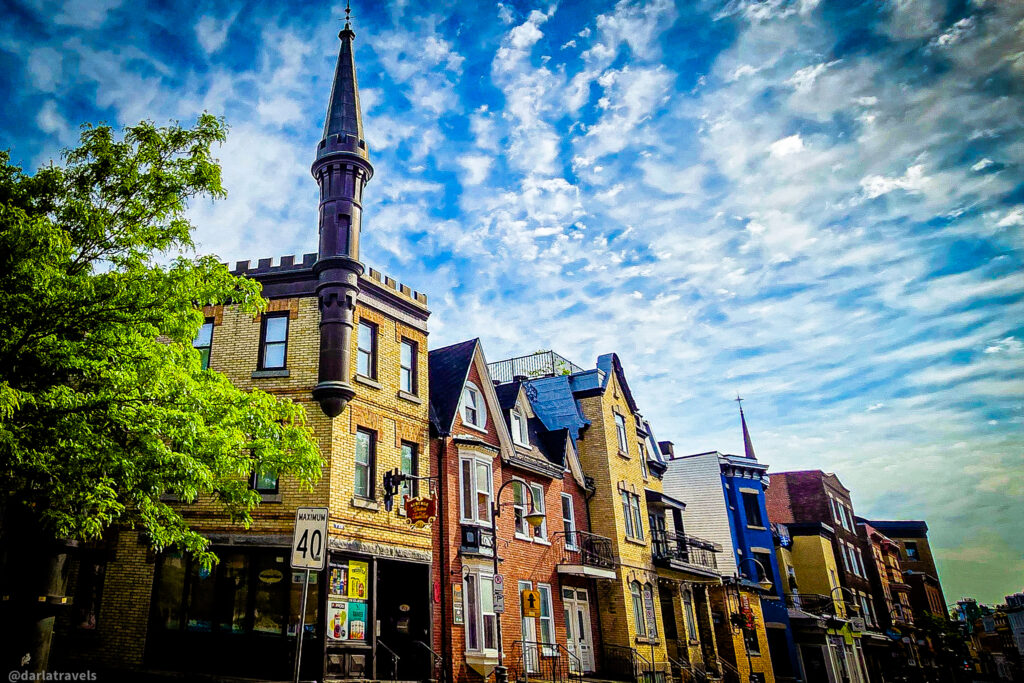 Architecturally diverse Quebec City street with turreted building (Auberge Château Des Tourelles) and tree-lined sidewalk