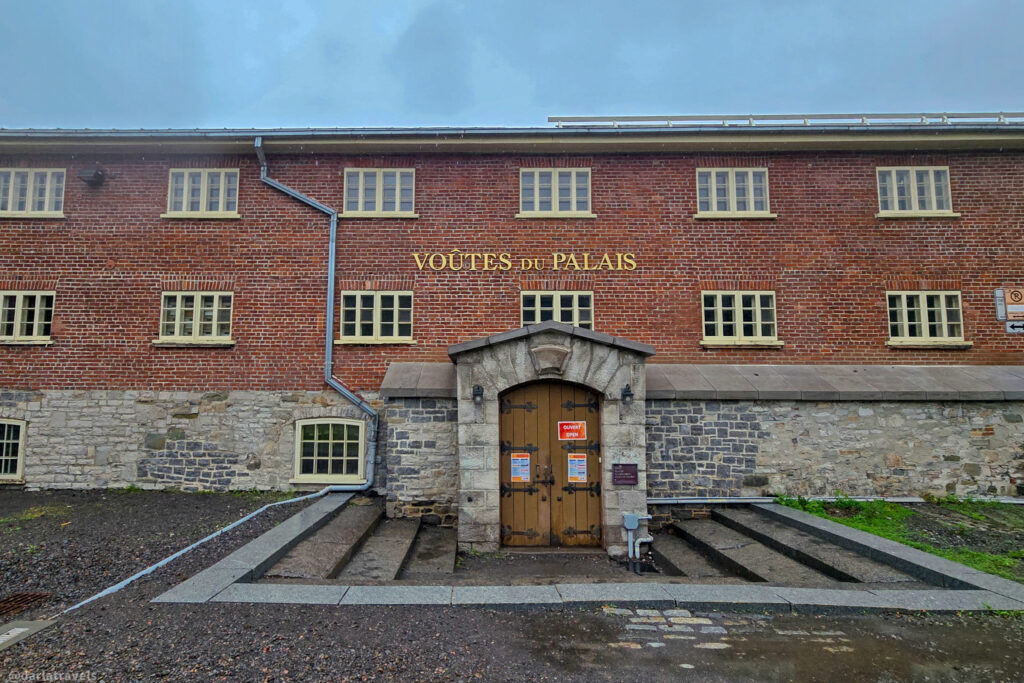 Historic brick and stone Voûtes du Palais building with arched doorway and posted signs in Quebec City