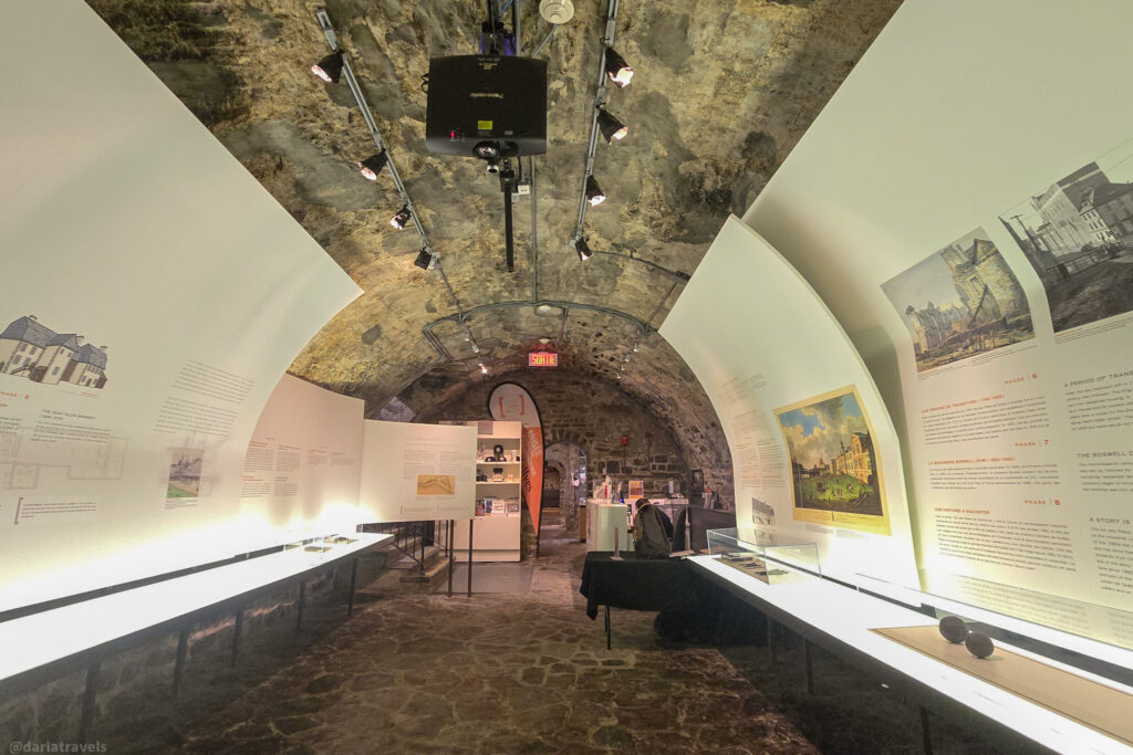 Stone-vaulted gallery with architectural history panels and illuminated displays in Quebec City museum