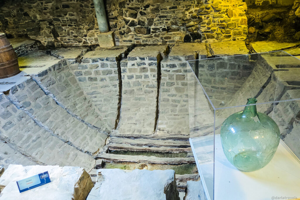 Historic stone basin and green glass bottle on display in Quebec City archaeological exhibit