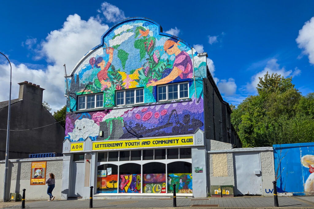 Letterkenny Youth and Community Club building with a colorful mural depicting people, nature, and the world map on its exterior.