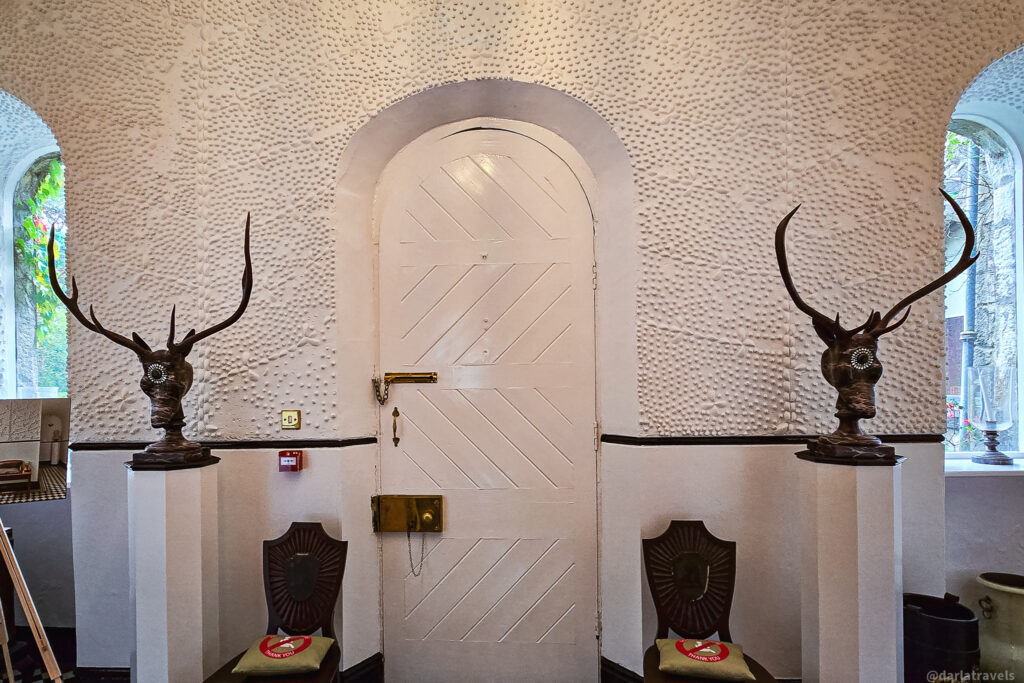 White door flanked by surreal busts with antlers and sunburst chairs in Glenveagh Castle interior