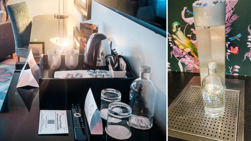 Hotel room refreshment station with kettle and coffee cups, empty glass bottle and glasses. Water refill station.