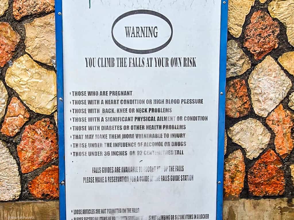 Safety sign listing health and height restrictions for climbing Dunn’s River Falls.