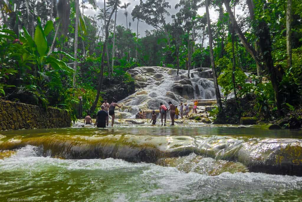 Visitors wading and climbing the natural rock steps of Dunn’s River Falls.