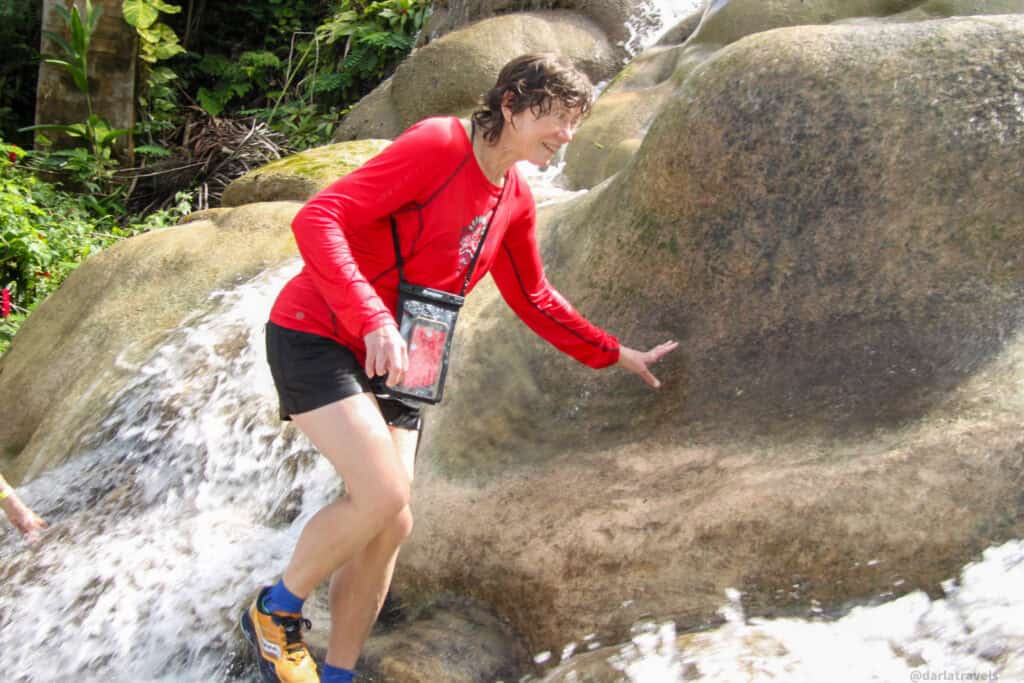 Visitor climbing a flowing rock section of Dunn’s River Falls during the ascent.