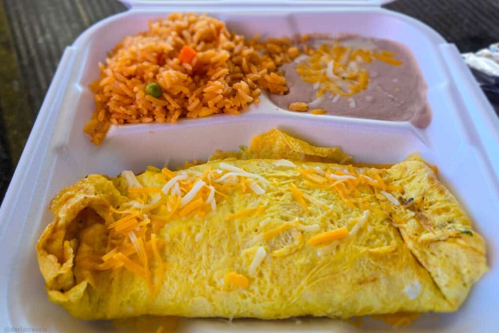 Spanish omelette with shredded cheese, Mexican rice and refried beans served in a white takeout container from a Moab taco shop