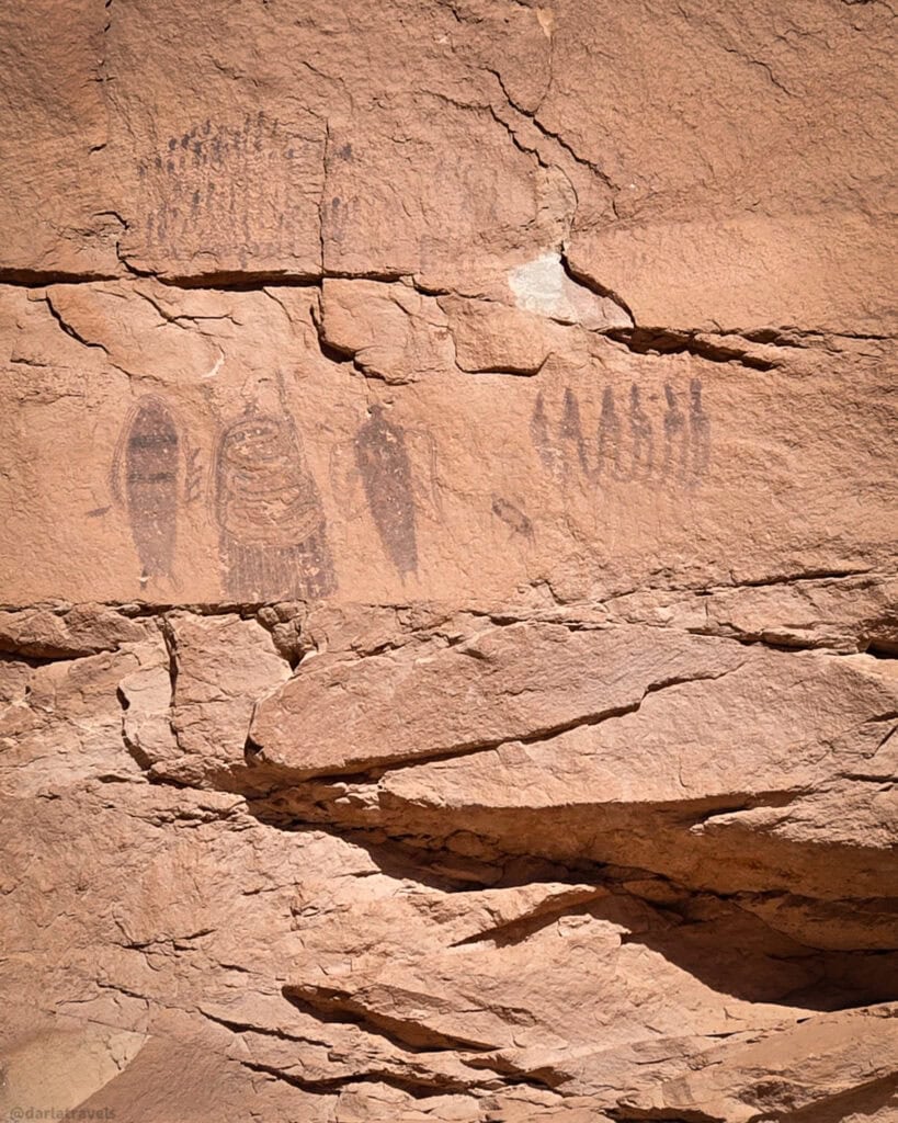 Human‑shaped rock art figures painted on weathered sandstone along a short walk near Moab