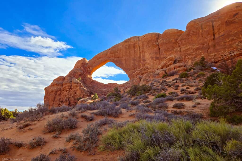 Broad sandstone arch above rocky desert slopes along a short hike in Arches National Park.