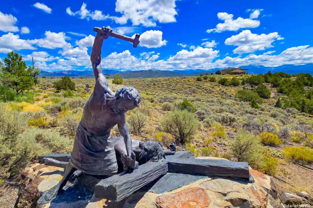 Bronze sculpture of Jesus being nailed to the cross at the Stations of the Cross Shrine on the mesa in San Luis Colorado