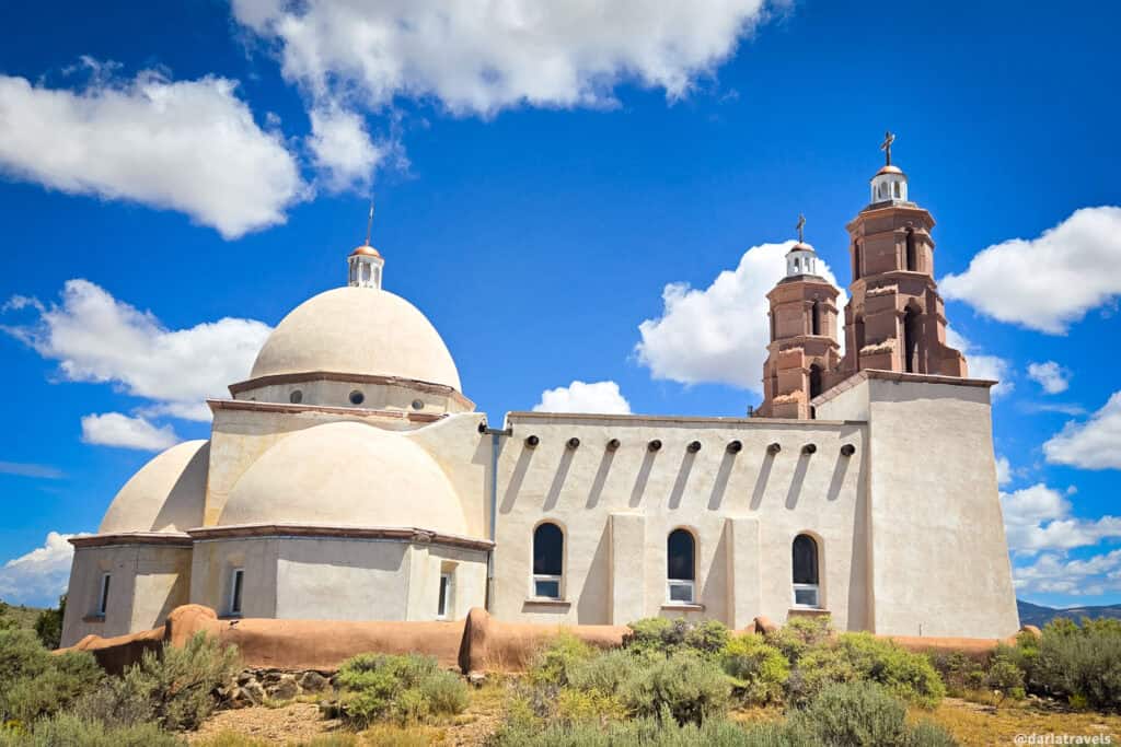 Adobe church with domed roof and twin brick bell towers at the San Luis Valley in Colorado under a blue sky