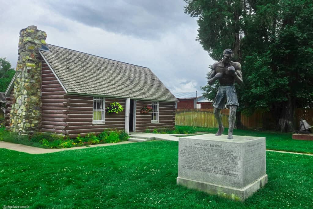 Bronze statue of boxer Jack Dempsey stands outside his log cabin birthplace, now a museum in Manassa Colorado