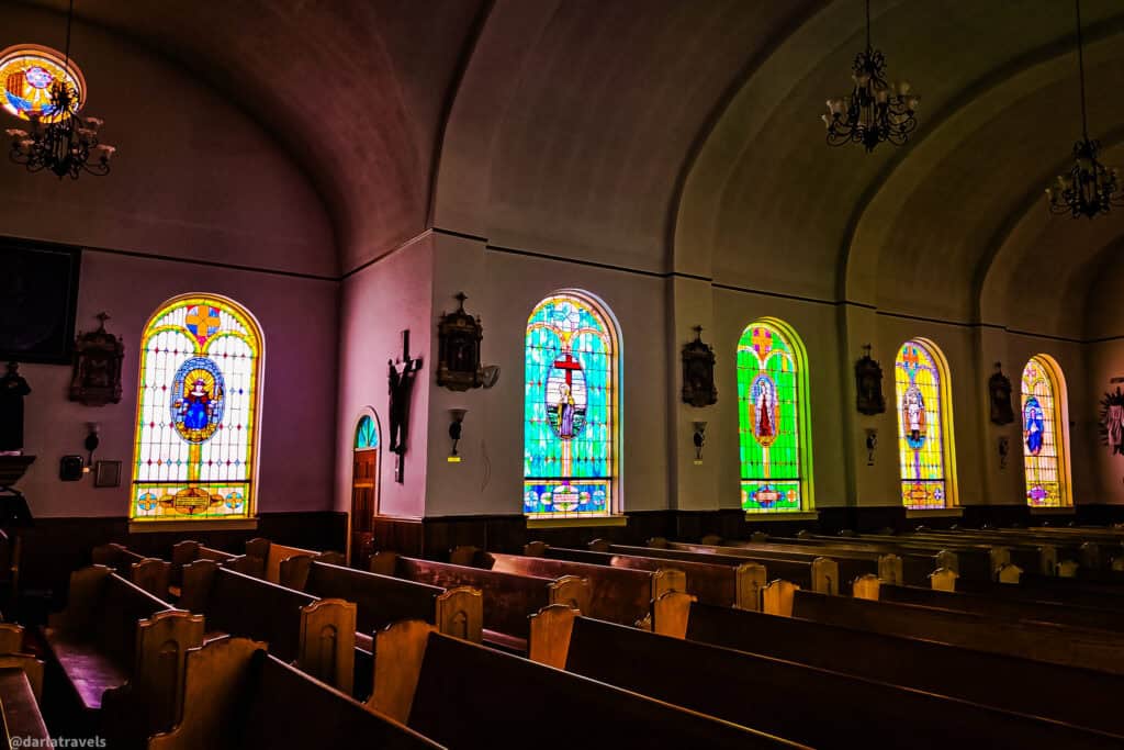 Stained glass windows and wooden pews inside Our Lady of Guadalupe Parish Church in Conejos Colorado