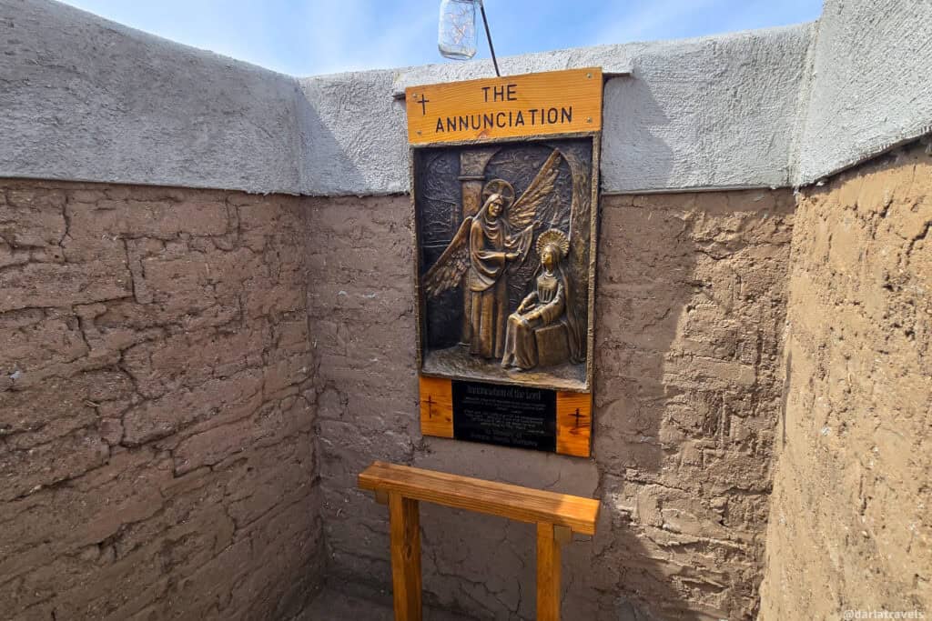 The Annunciation bronze relief by Lynn Kircher with wooden kneeling bench inside a niche at the Conejos Colorado labyrinth