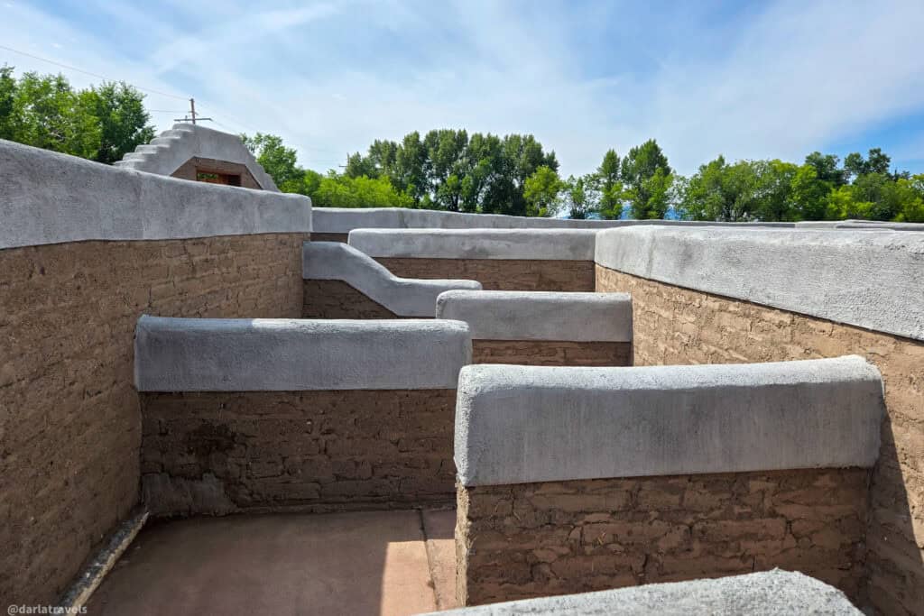 Close-up view of adobe and gray plaster walls inside the Conejos Colorado labyrinth