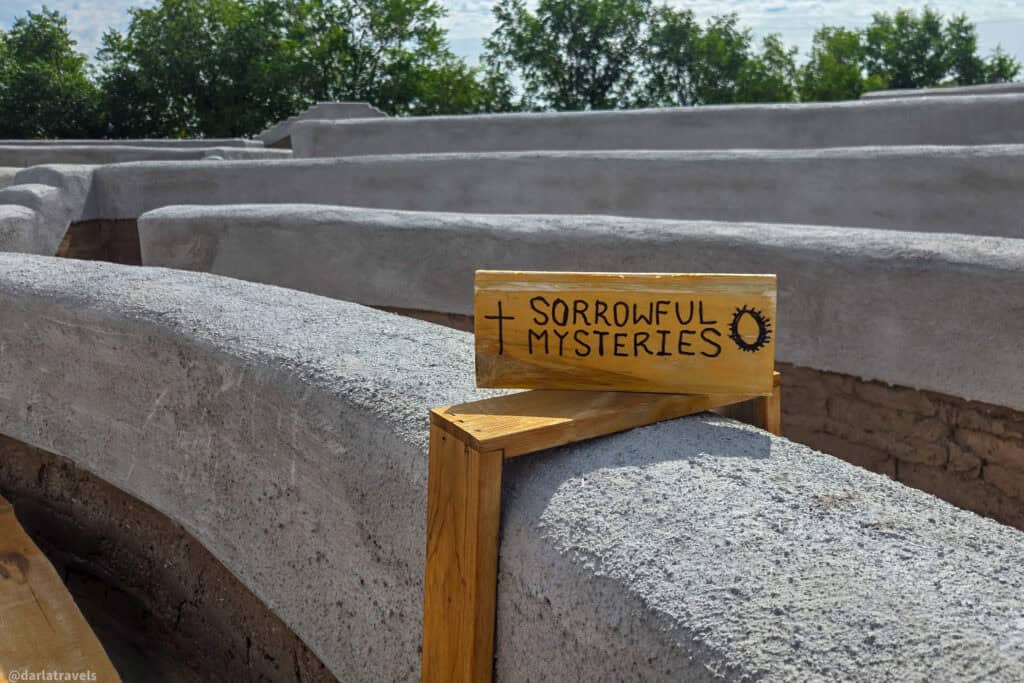 Sorrowful Mysteries sign on handcrafted adobe wall at the Rosary labyrinth in Conejos Colorado