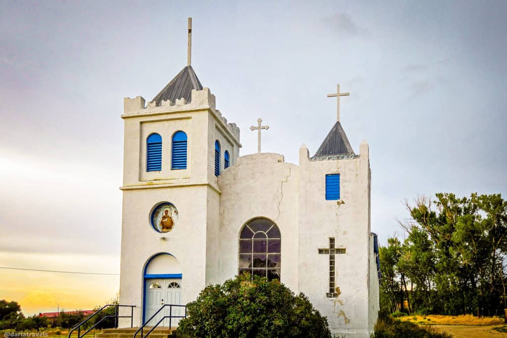 Front view of white adobe mission church with blue shutters and twin towers in southern Colorado
