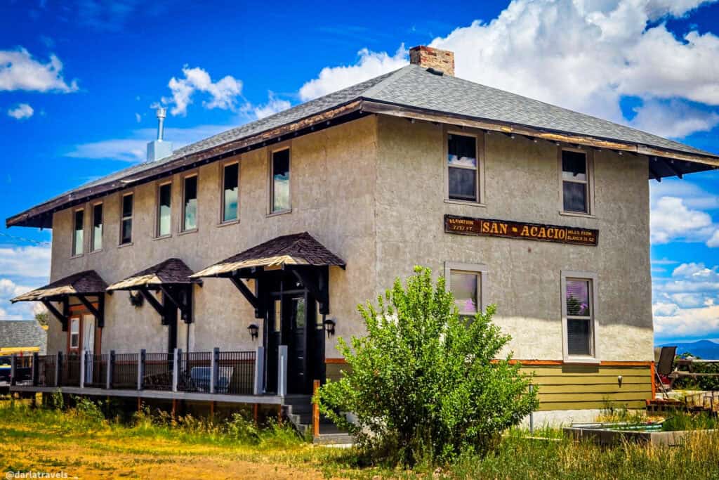 Historic wo-story adobe train depot building with San Acacio elevation sign reading 7,737 feet in San Luis Valley, Colorado