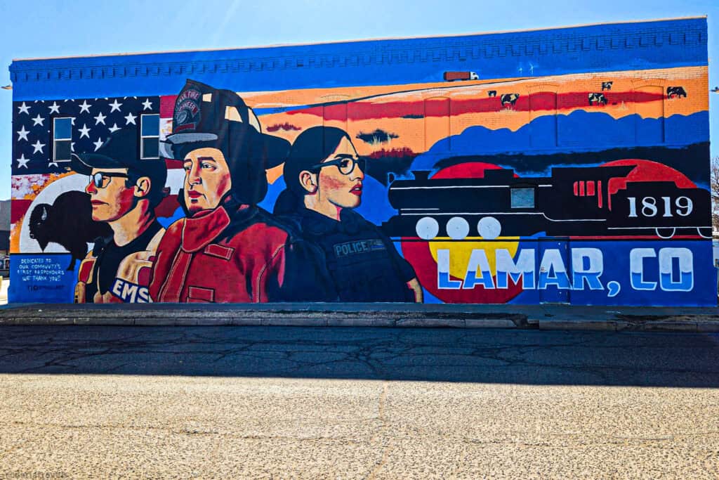 Colorful street mural in Lamar, Colorado, honoring EMS, fire, and police with plains, train, and flag imagery