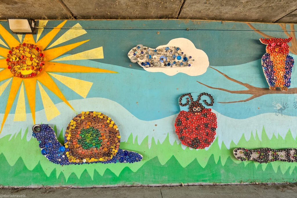 Wall art features a sun, cloud, owl, snail, ladybug, and caterpillar made of colorful quilled paper.