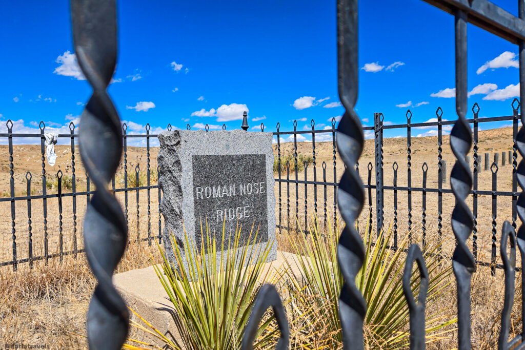 Stone marker reading "Roman Nose Ridge" behind a black metal fence