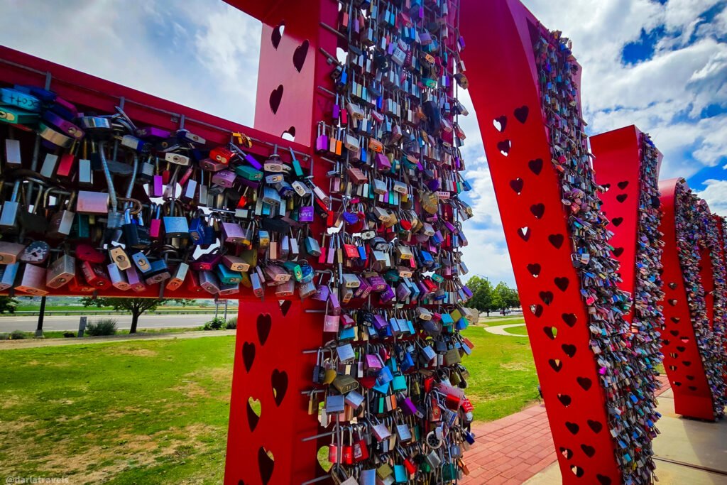 Close-up of colorful padlocks attached to a large red metal “LOVE” sculpture with heart-shaped cutouts in Loveland, Colorado.