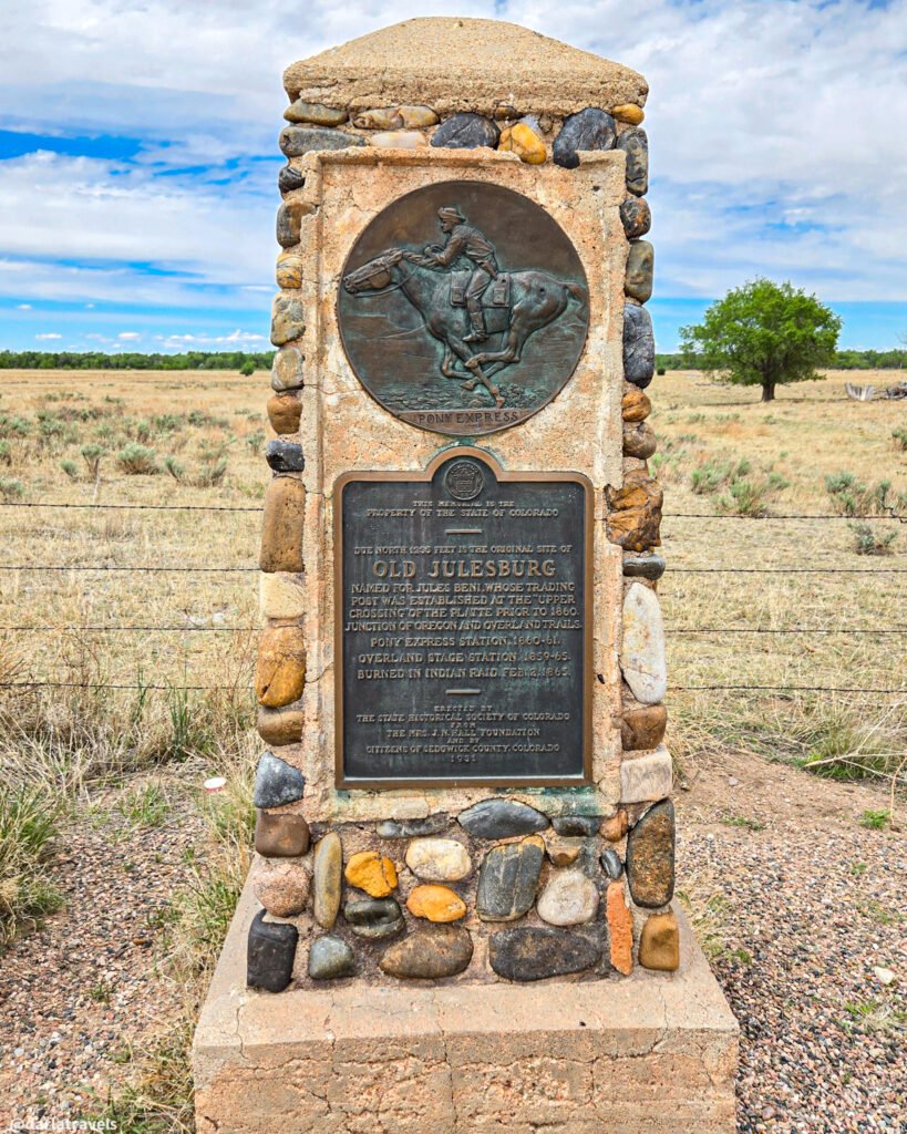 Old Julesburg stone monument with a Pony Express rider relief above a historical plaque.