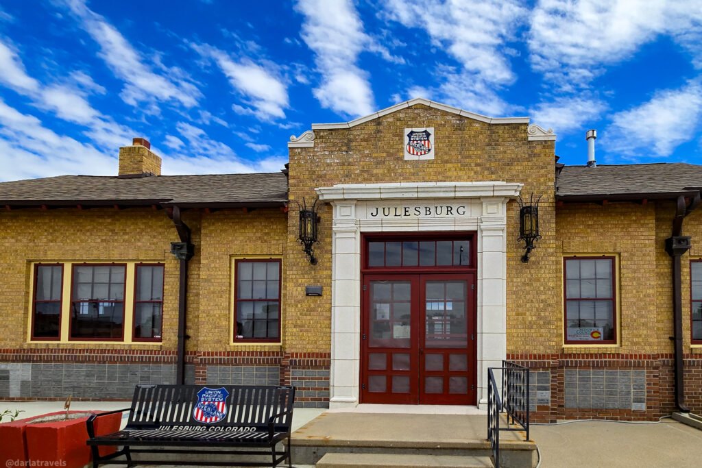 Julesburg Depot Museum exterior with yellow brick, red double doors, and a Union Pacific emblem.