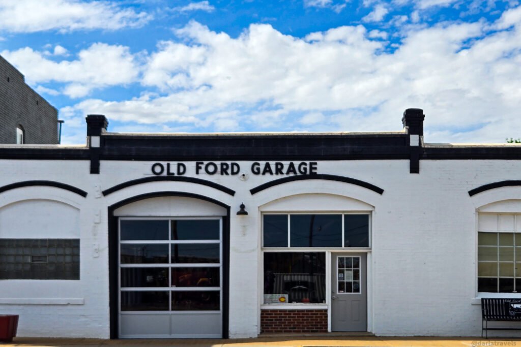 Old Ford Garage in Julesburg, with a white facade, black arched trim, and a glass-paneled garage door.