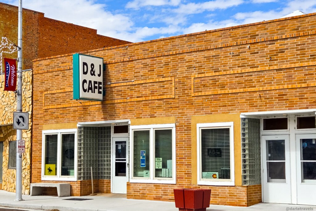 D & J Cafe’s brick storefront in Julesburg, with a projecting sign and glass-block entrance surround.