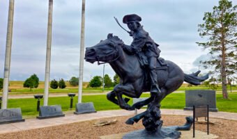 Pony Express rider sculpture on a galloping horse, surrounded by station markers in Sidney, Nebraska.