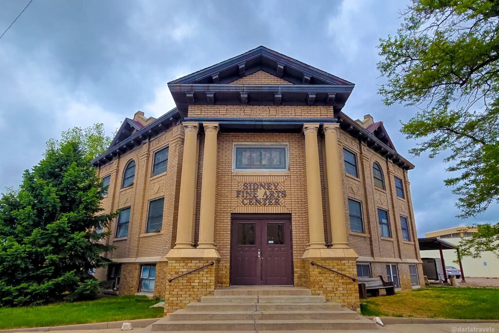 Sidney Fine Arts Center’s yellow-brick facade, with paired columns and steps leading to the entrance.