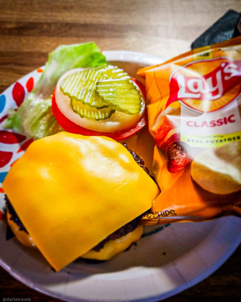 Julesburg Tavern cheeseburger with lettuce, tomato, onion, pickles, and potato chips.